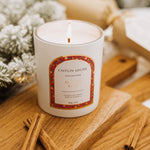 Caitlin Louise Collection Festive Spice Scented Christmas Candle styled with Christmas tree on brown board with cinnamon sticks