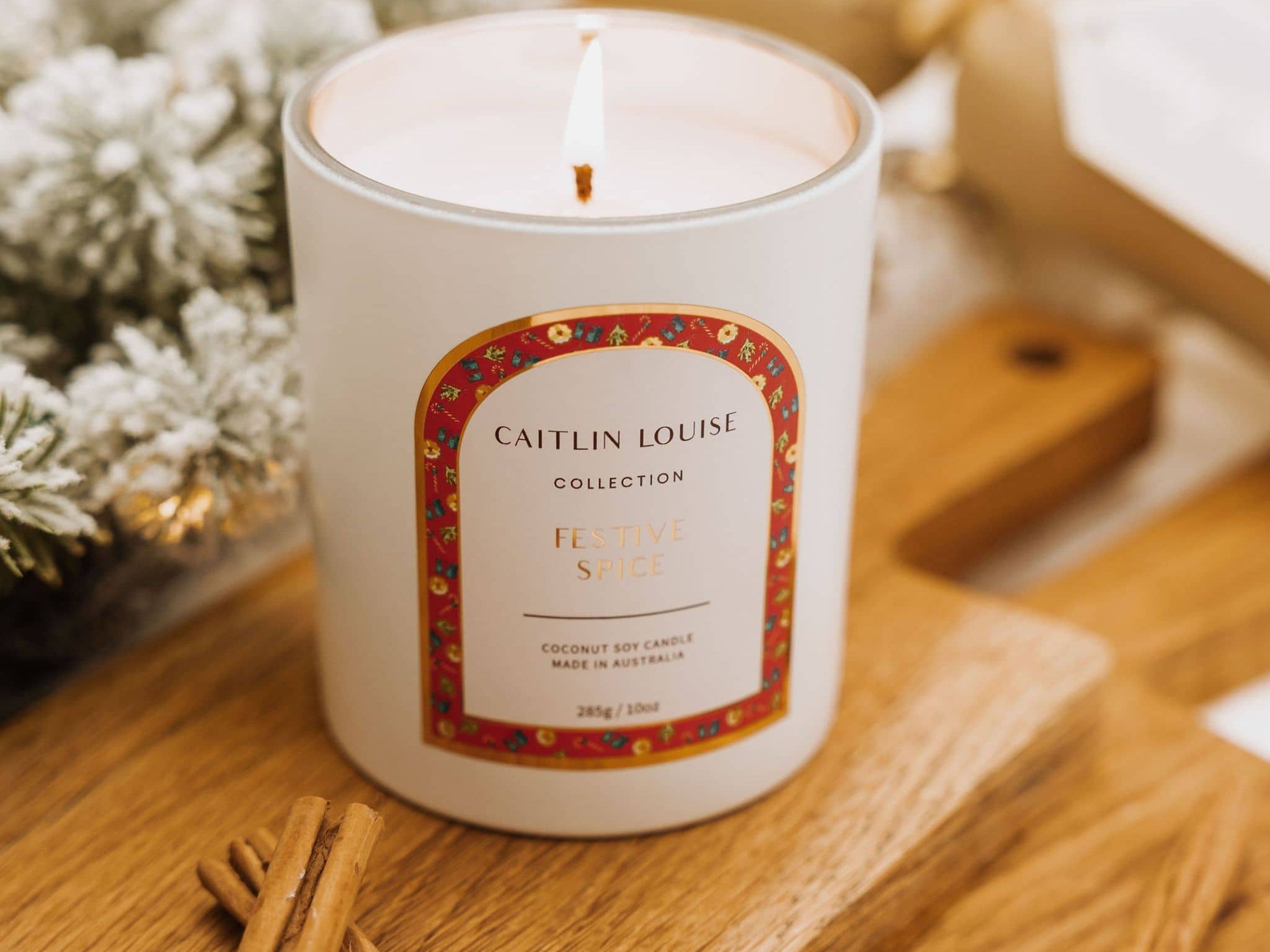 Caitlin Louise Collection Festive Spice Scented Christmas Candle styled with Christmas tree on brown board with cinnamon sticks