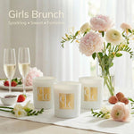 Caitlin Louise Collection Candles and glasses of champagne on a table with flowers and fruit.