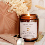 Scented Candle with a label 'Give Me That Slow Burn Romance' from Caitlin Louise Collection, surrounded by decorative elements.