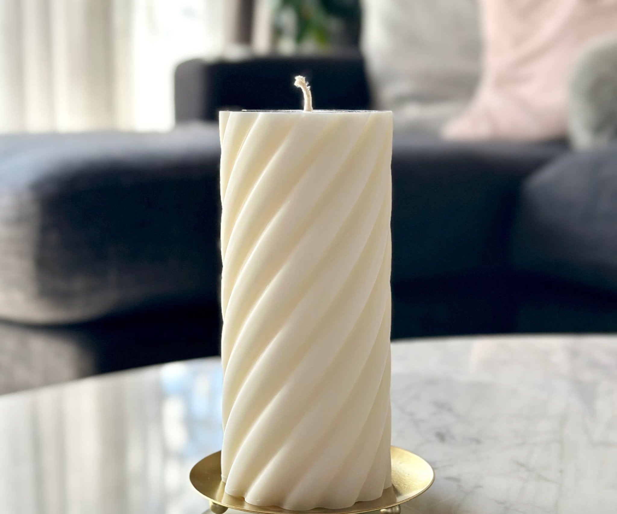 Pillar candle sitting on gold candle plate on coffee table