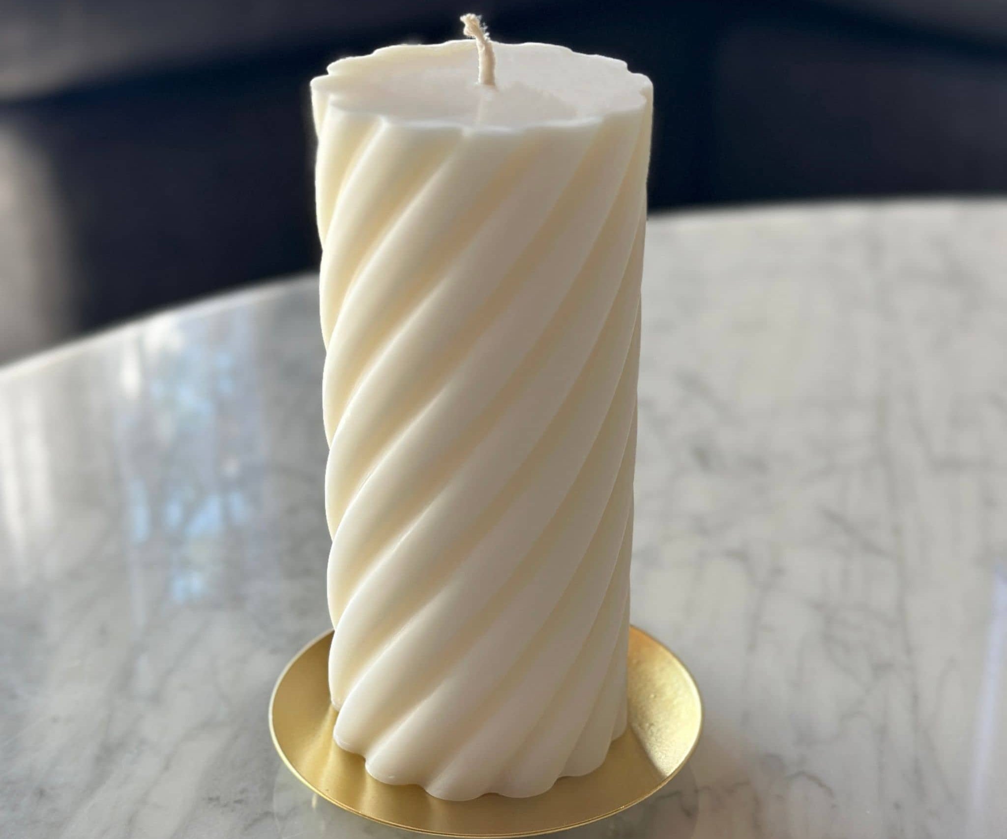 Pillar candle sitting on gold candle plate on coffee table - shot from high angle