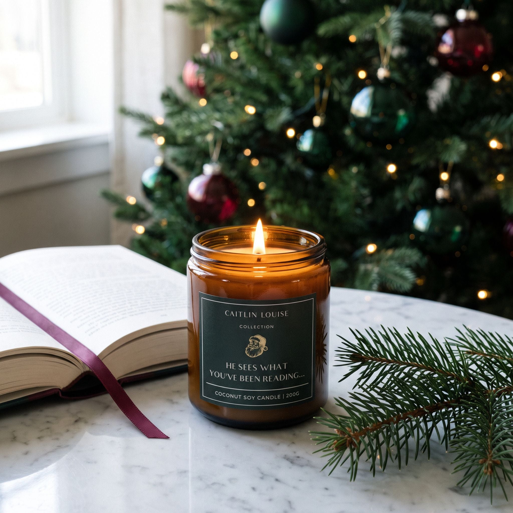 Christmas bookish candle on marble table with open book nearby and christmas tree background