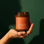 Bookish candle held in hand on emerald background
