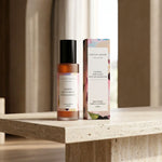 Room spray bottle and packaging on a wooden surface with a neutral background