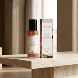 Room spray bottle and packaging on a wooden surface with a neutral background