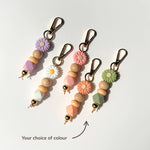 Set of colorful beaded keychains with floral attachments on a white background.