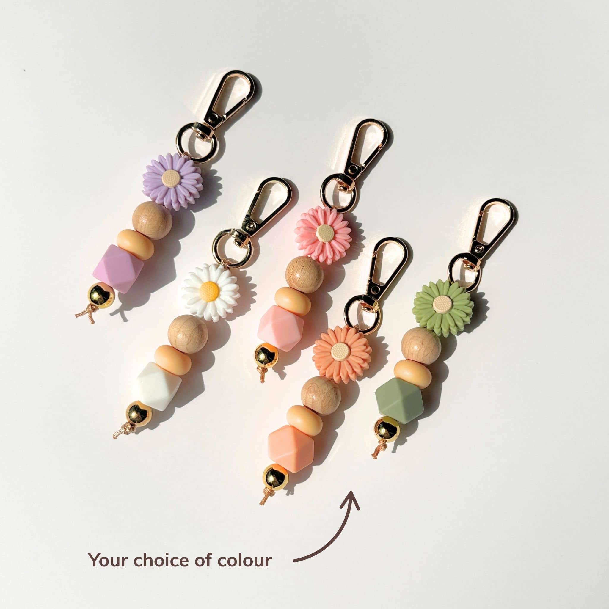 Set of colorful beaded keychains with floral attachments on a white background.