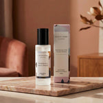 Room spray bottle and packaging on a wooden surface with a blurred background