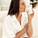 A lady sitting on a lounge smelling a Caitlin Louise Collection Bijou candle