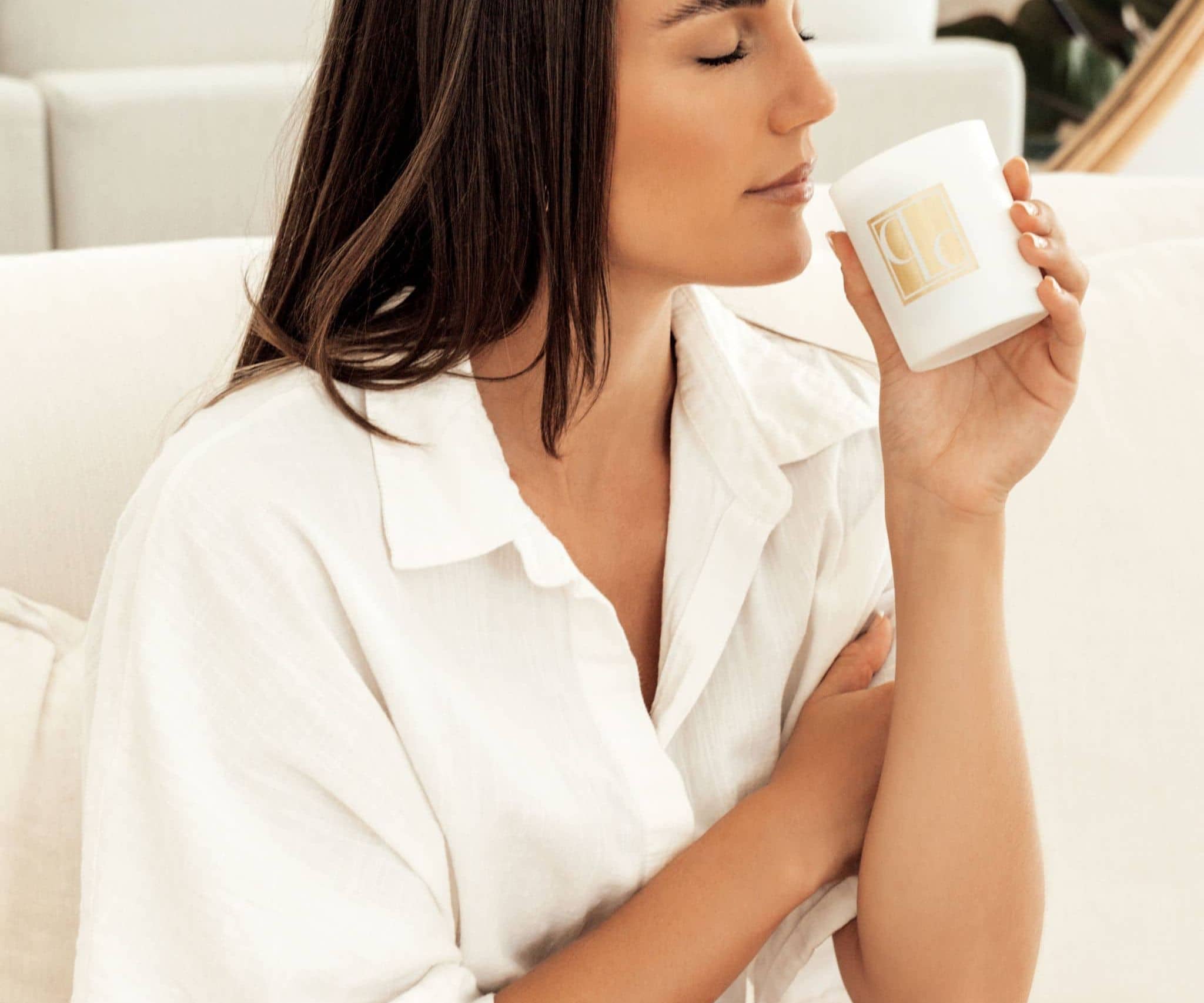 A lady sitting on a lounge smelling a Caitlin Louise Collection Bijou candle