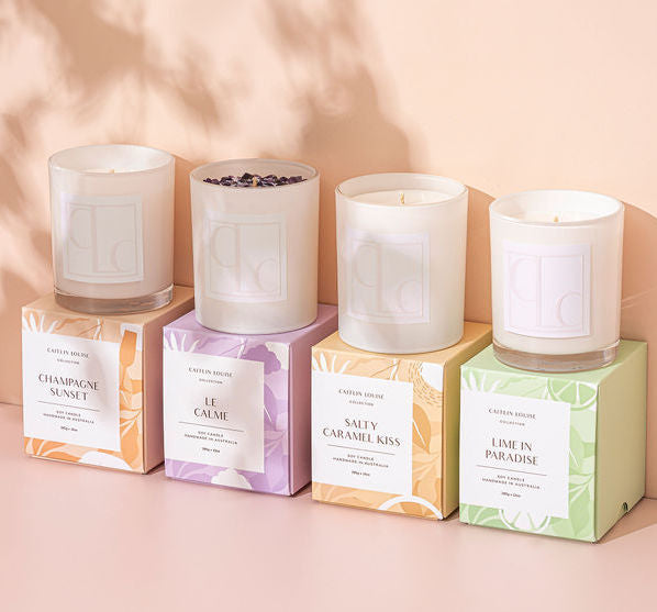 Caitlin Louise Collection's Core candle collection - lined up boxes with candles on top - apricot background with shadows of leaves