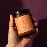 hand holding candle with orange label saying 'new book? cancel my plans' against purple background