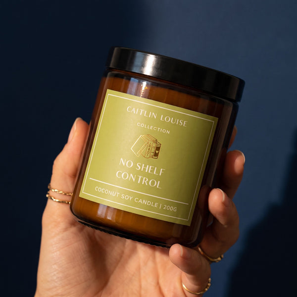 hand holding candle with green label saying 'no shelf control' against navy coloured background