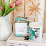 Candle with packaging and pink tulips on a surface