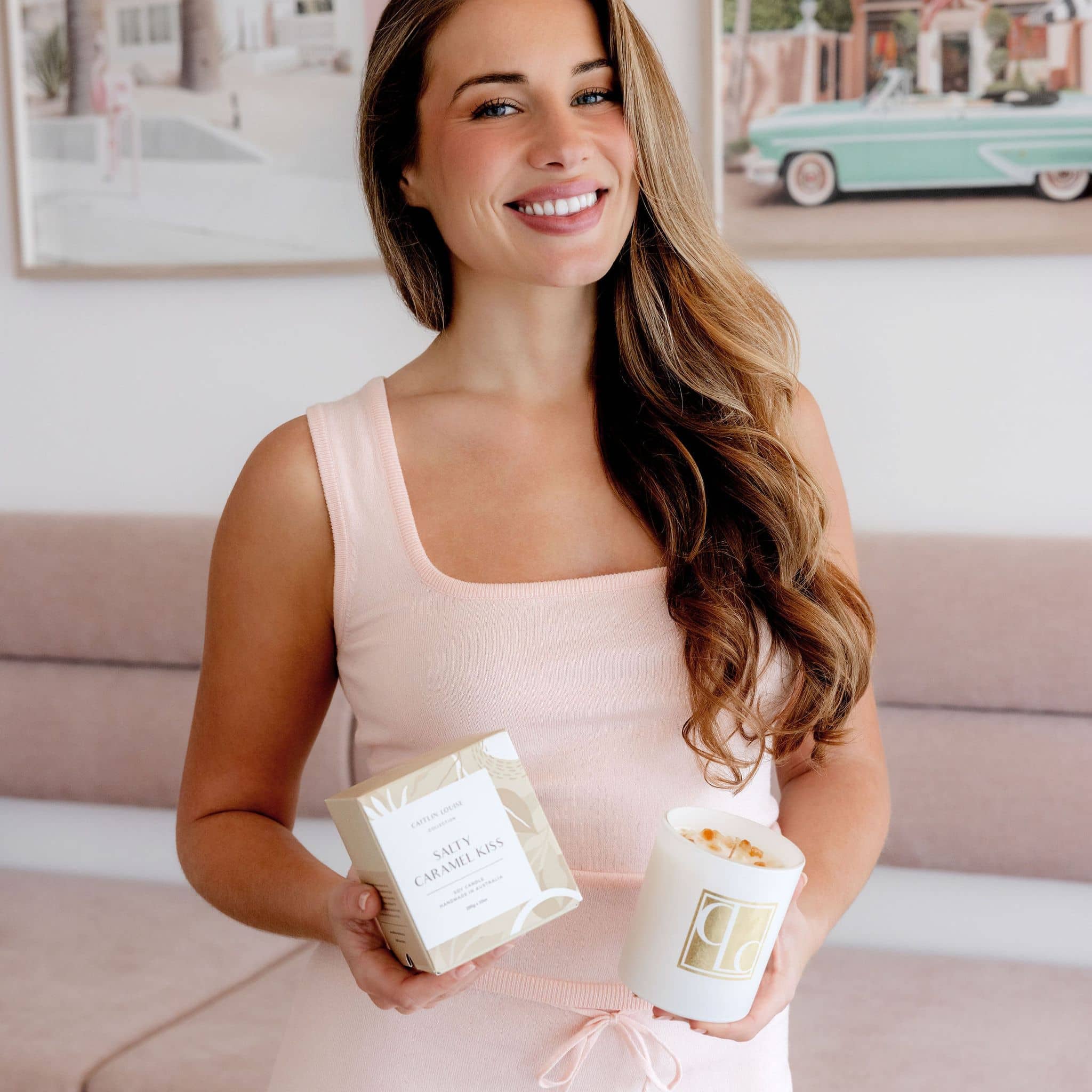 Model holding Salty Caramel Kiss crystal infused candle and box - pink background