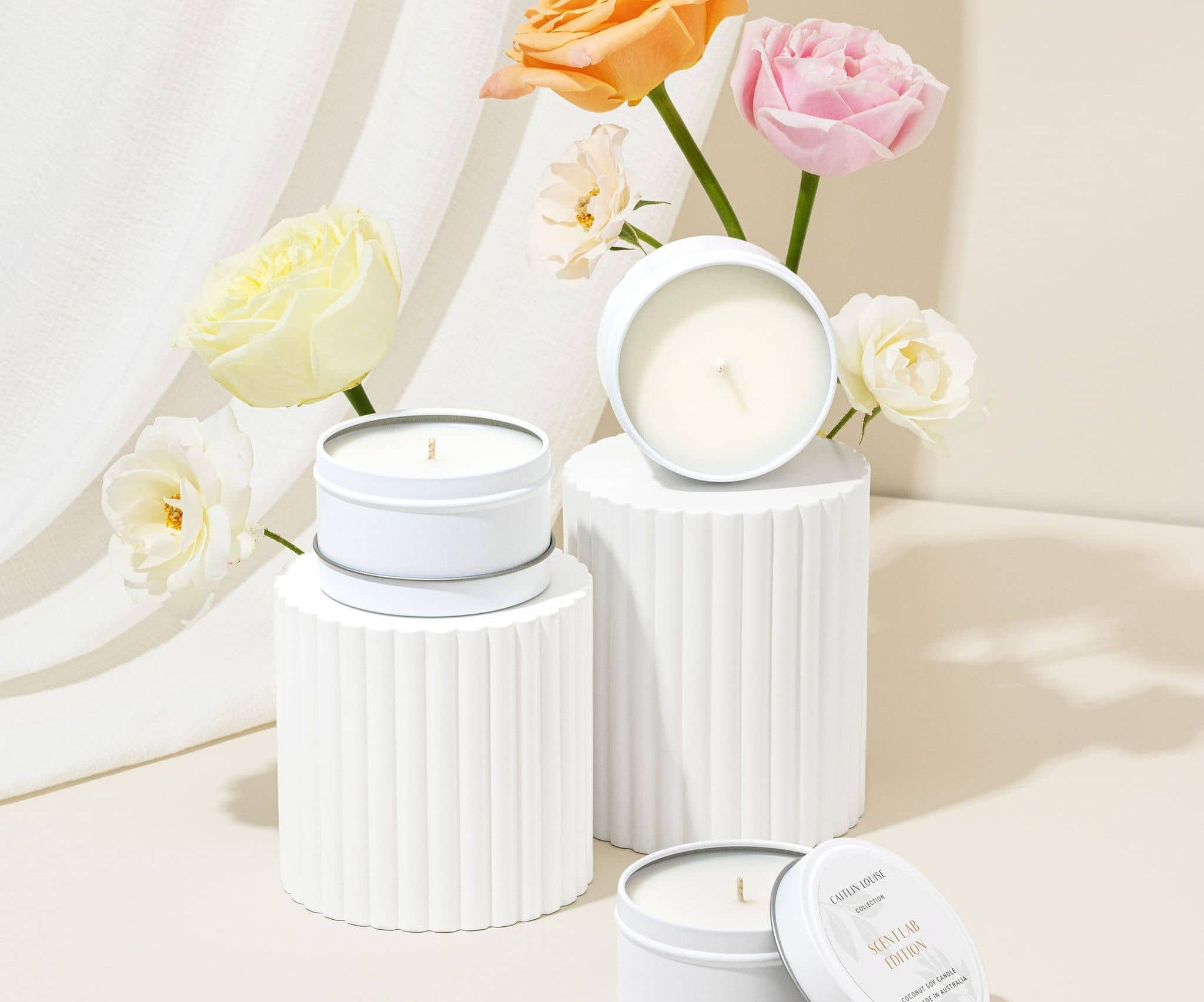 Scent Lab Edition candles styled on blocks with flowers behind them
