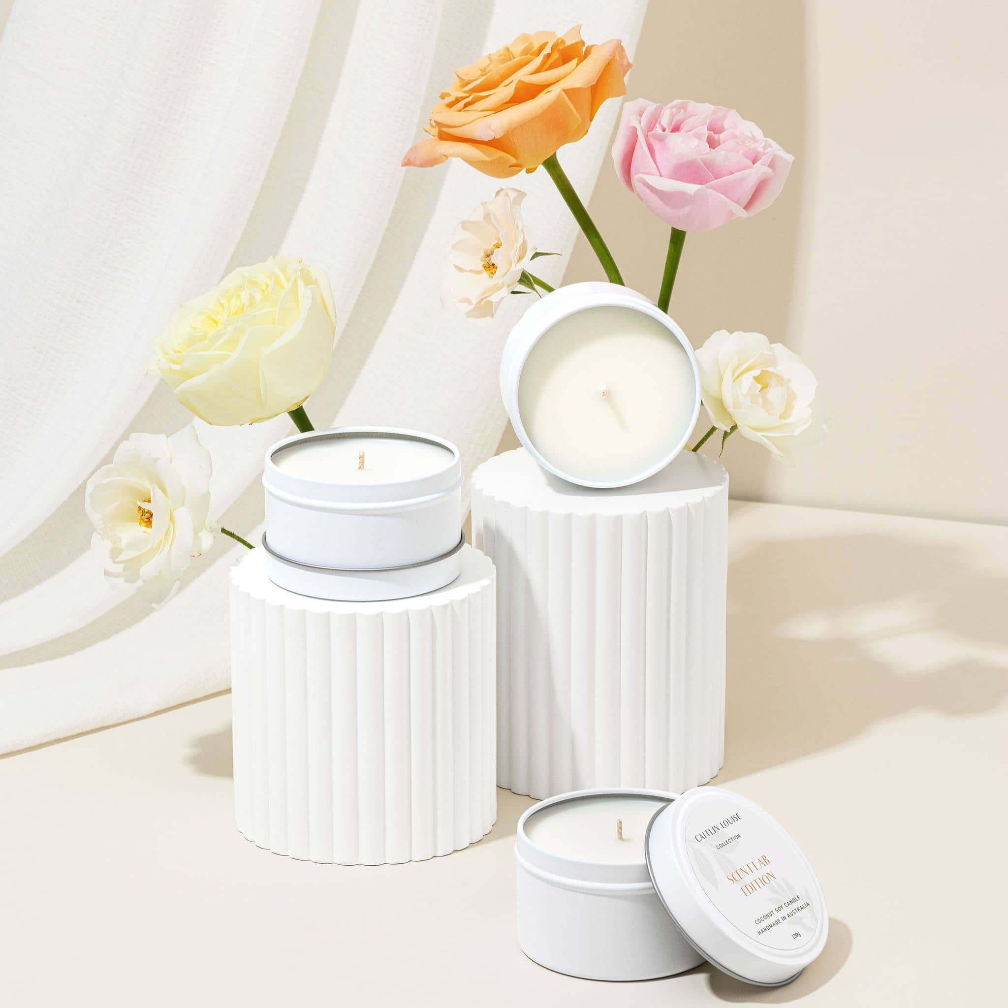 Scent Lab Edition candles styled on blocks with flowers behind them