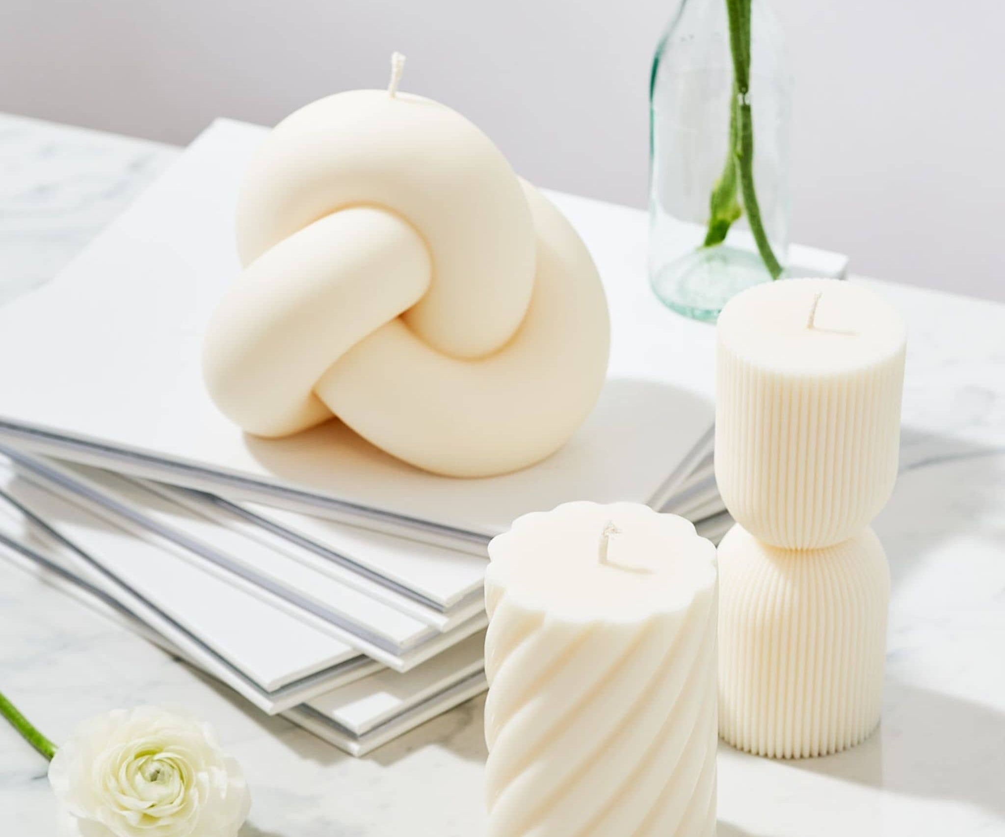 Caitlin Louise Collection sculptural candles - Knot, Aurelia, Symphony styles on books with flowers