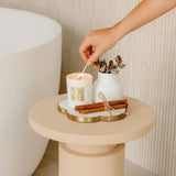 Hand lighting a candle on a small round table with decorative elements.