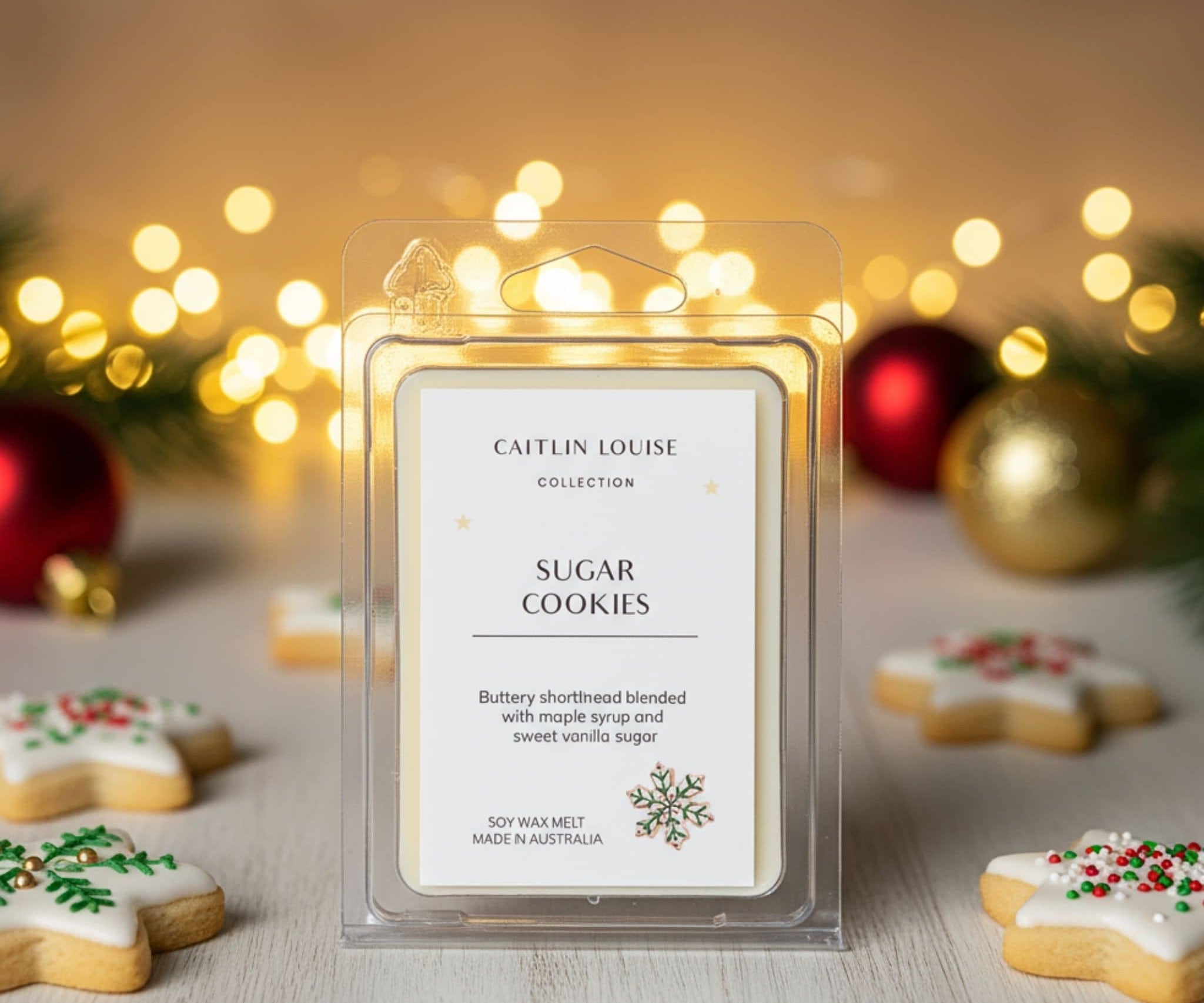 Wax melt packaging labeled 'Sugar Cookies' by Caitlin Louise with Christmas decorations in the background.