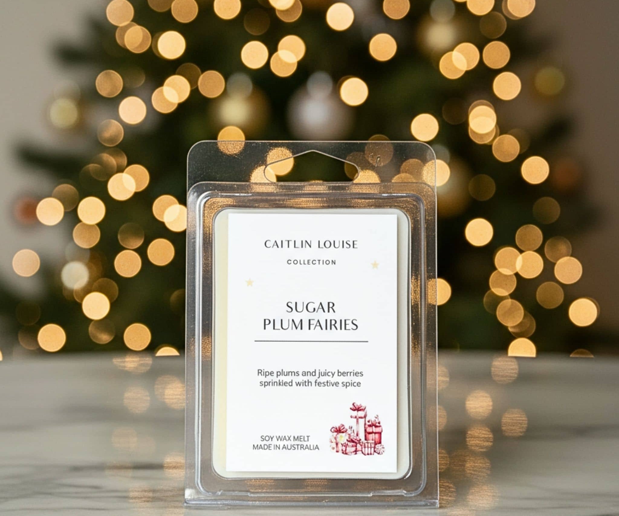Caitlin Louise Sugar Plum Fairies wax melt packaging with a blurred Christmas tree in the background