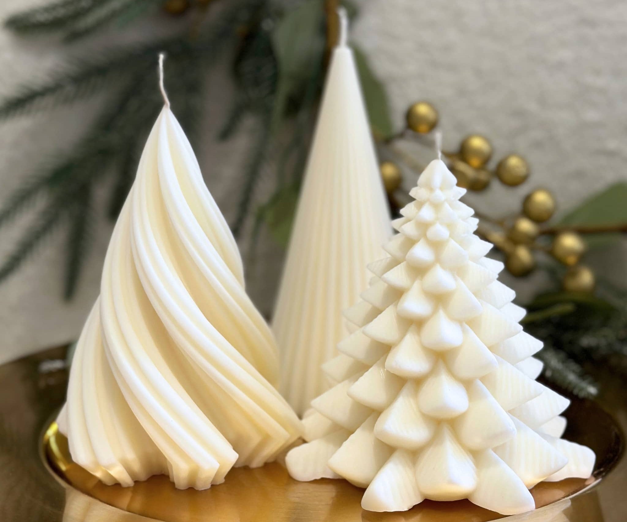 Caitlin Louise Collection trio of Christmas Tree Pillar candles - styled on gold plate with festive wreath in background.