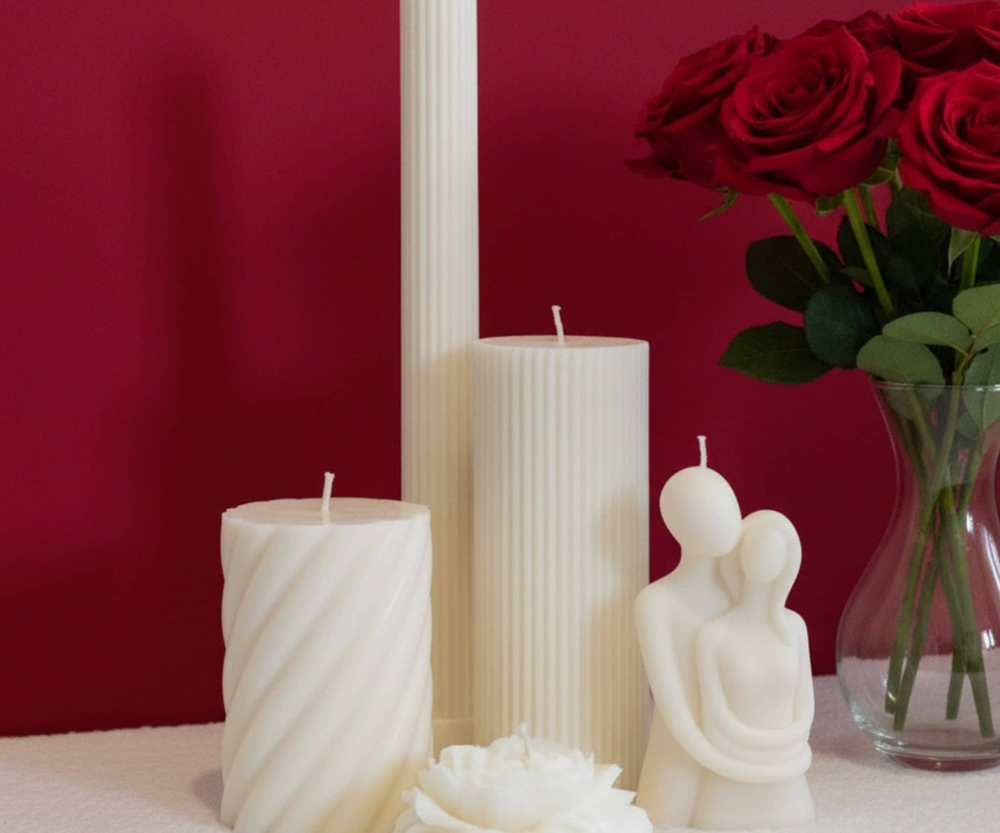 Bundle of decorative candles for Valentines Day - red background with roses in vase