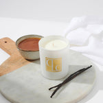 Caitlin Louise Collection Vanilla Caramel Scented Candle on board with bowl of caramel in background and vanilla sticks in the foreground.