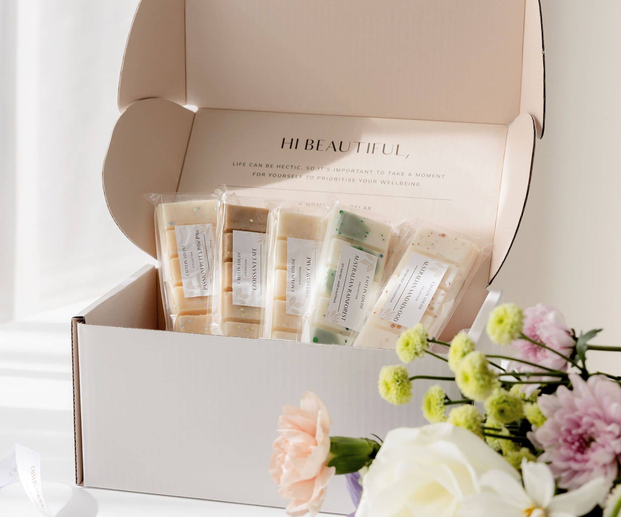 Subscription box containing wax melts with a bouquet of flowers on a white background