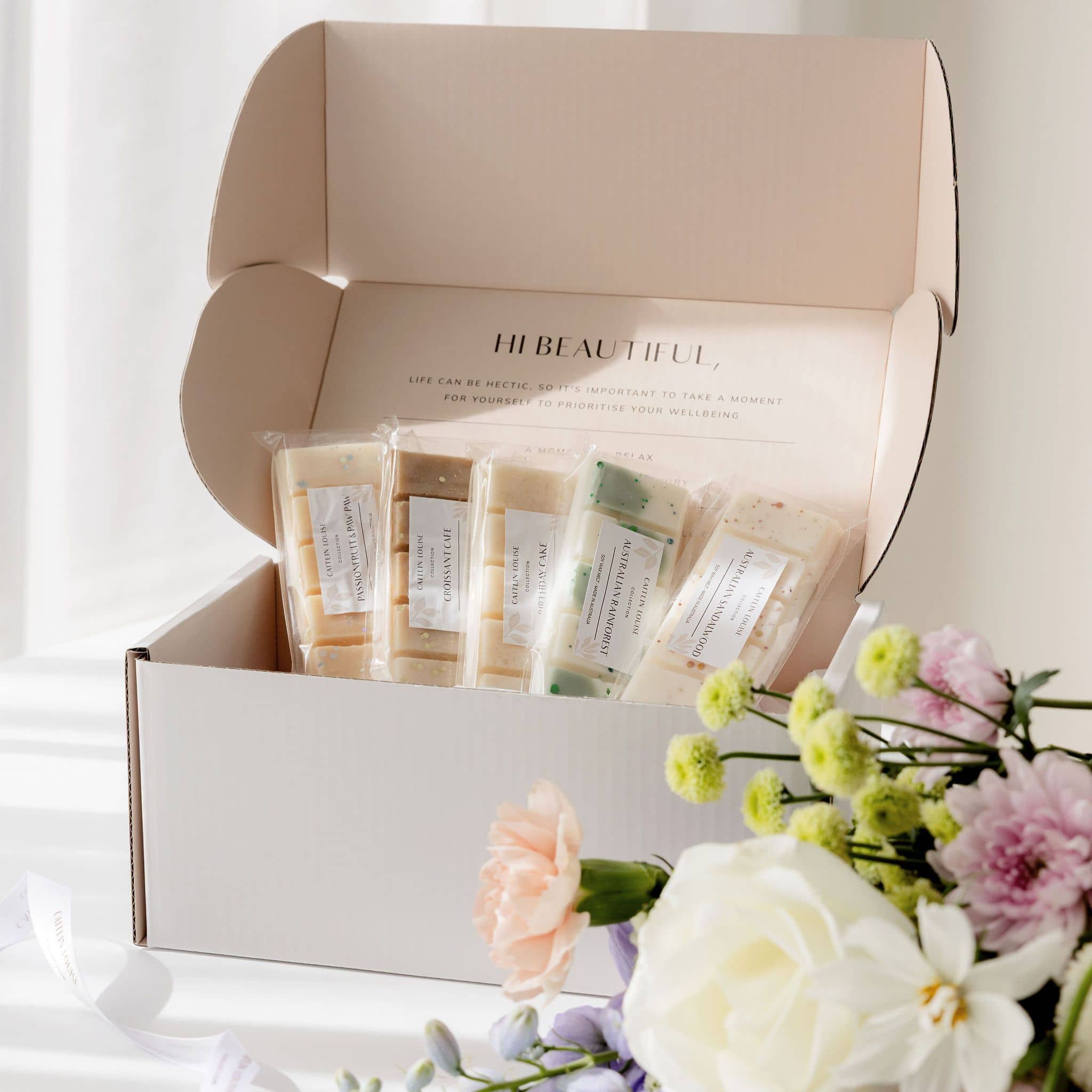 Subscription box containing wax melts with a bouquet of flowers on a white background