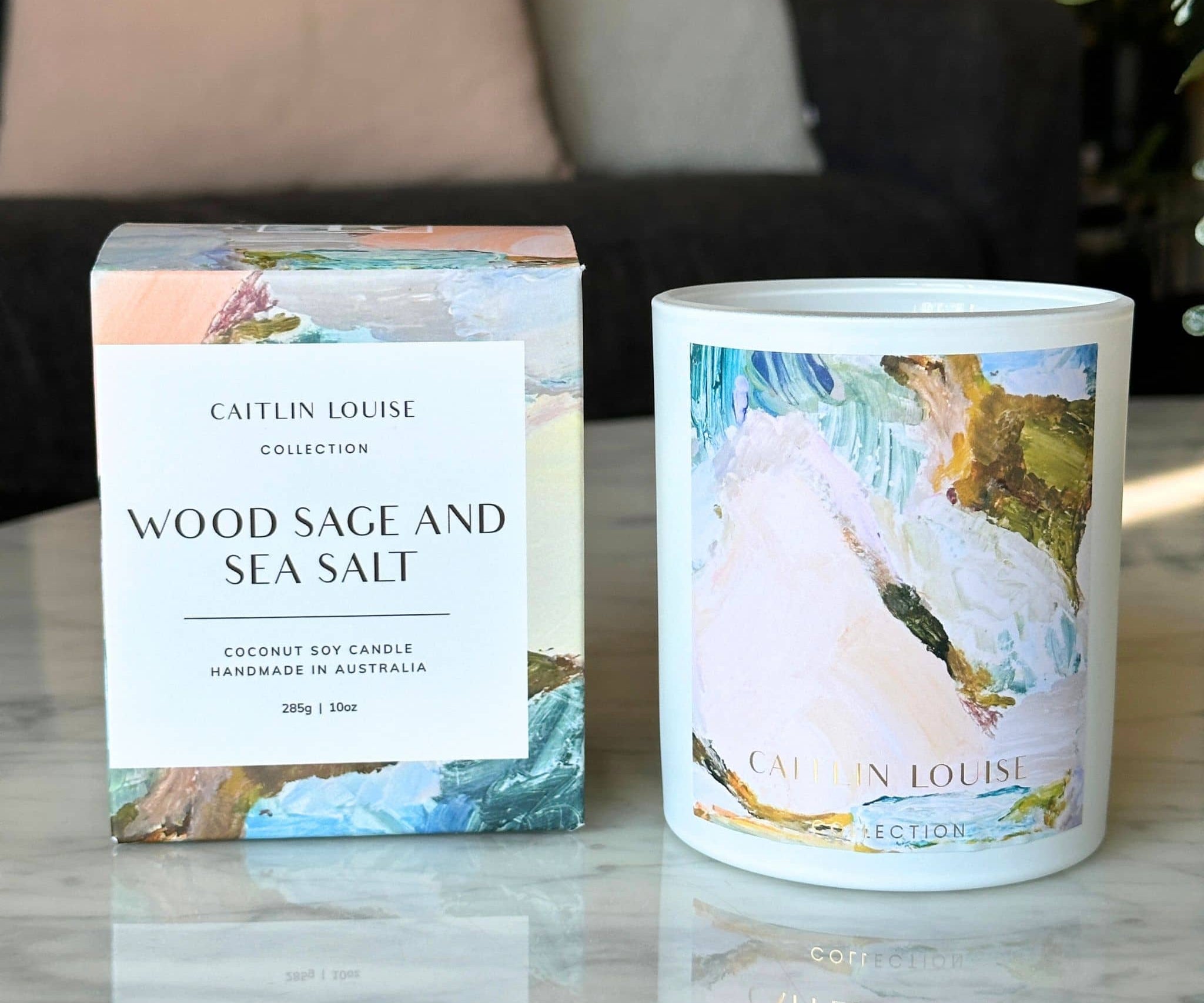 Wood sage and sea salt artist candle next to box on coffee table